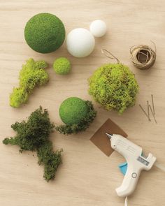 moss balls, scissors and glue sitting on top of a wooden table