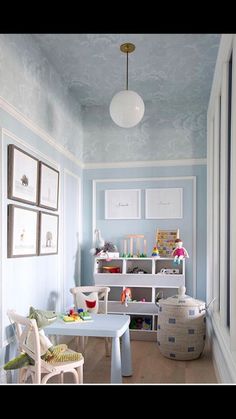 a child's playroom with blue walls and white furniture, including a table and chairs