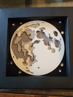 a shadow box with a paper cut out of the earth in it's center