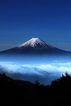 a mountain covered in clouds under a blue sky