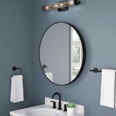 a bathroom sink with a round mirror above it