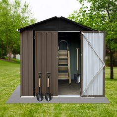 an outhouse with the door open and two shovels in front of it on grass