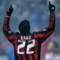 a soccer player raising his arms in the air with one hand up and two fingers raised