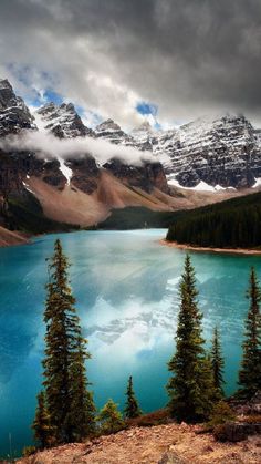 the mountains are covered in snow and clouds as they sit on top of a blue lake