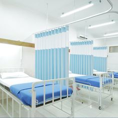 a hospital room with blue and white drapes hanging from the ceiling, two beds on each side