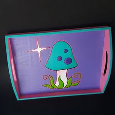 a blue and purple tray with a mushroom painted on the bottom, in front of a black background