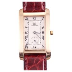 Classic and elegant Verdura watch, in 18k rose gold, sleek rectangular case, measuring 24mm excluding the crown x 40mm, with brownish-burgundy non branded leather bracelet and a steel gold tone generic buckle. The band is in unworn condition, 8" long. Silvered dial with black Roman numeral markers, small seconds sub-dial at 6 o'clock position. Quartz/battery movement. Antique Style Gold Rectangular Watch Accessories, Rose Gold Rectangular Watch Accessories For Formal Events, Formal Brown Watch Accessories With Rectangular Dial, Brown Rectangular Watch Accessories For Formal Occasions, Classic Red Watches For Formal Occasions, Brown Rectangular Watch For Formal Occasions, Classic Red Watch For Formal Occasions, Formal Rose Gold Rectangular Watch Accessories, Formal Brown Rectangular Watch Accessories