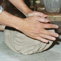 a person is kneading something on top of a piece of pottery with their hands