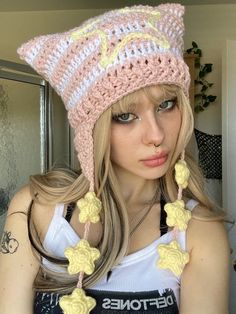 a girl with long blonde hair wearing a crocheted hat and earring set