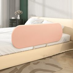 a bed with a pink pillow on top of it next to a dresser and window