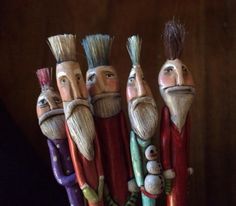 four wooden toy figurines with different colored hair and beards on their heads