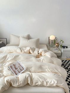 an unmade bed in a white room with black and white checkered flooring