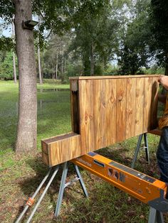 a man standing next to a wooden box on top of a metal platform in the grass