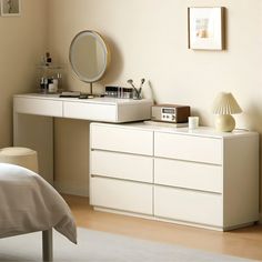 a bedroom with a dresser, mirror and lamp on the side table next to a bed