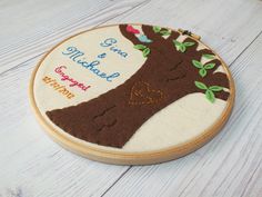 a wooden hoop with a tree and hearts on it, sitting on a white table