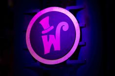 a w logo lit up in the dark with purple lighting on it's side