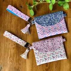 three small purses with tassels on top of a wooden table next to a potted plant