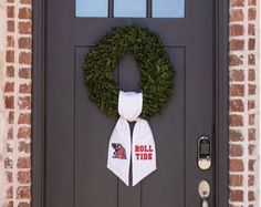 a wreath is hanging on the front door of a brick building with a football tie tied to it