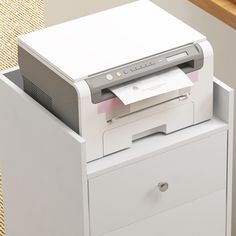 a printer sitting on top of a white cabinet