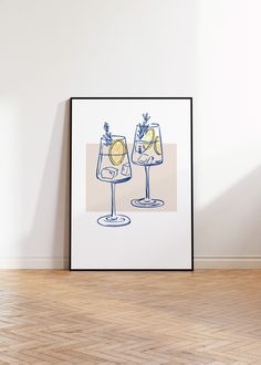 two wine glasses with lemons and pineapple on them are sitting in front of a white wall