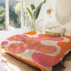 a bed with an orange and pink comforter