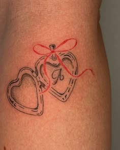 a woman's stomach with two heart shaped lockes on it and a red ribbon