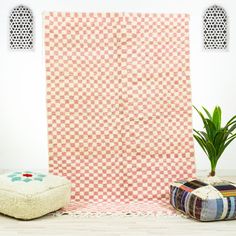 a room with a rug, ottoman and potted plant