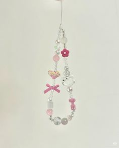 a pink and white beaded necklace hanging from a hook on a wall next to a teddy bear