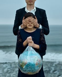 a man covering his eyes while holding a bag with the earth in it's hands