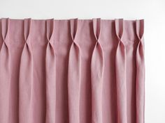 pink curtains with pleated edges hanging on a wall