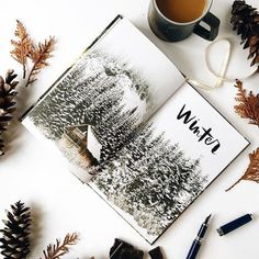 an open book sitting on top of a white table next to a cup of coffee