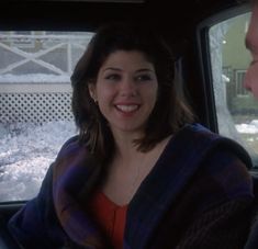 a woman sitting in the back seat of a car with a man standing next to her