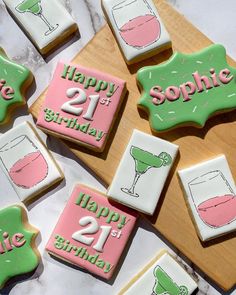 decorated cookies with happy 21st birthday designs on a wooden board and white marble counter top