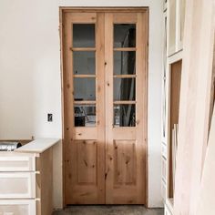 an empty room with two wooden doors and drawers on the floor next to a desk