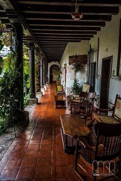 an empty porch with wooden chairs and tables