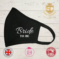 the bride to be face mask is shown on a white wooden background with two badges