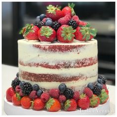 a multi layer cake with berries and strawberries on top