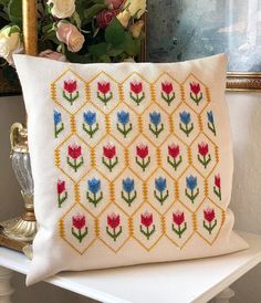 a white pillow sitting on top of a table next to a vase filled with flowers