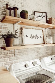 a white washer and dryer sitting in front of a brick wall