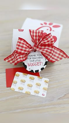 a thank you card with a red bow on it and some cookies in front of it