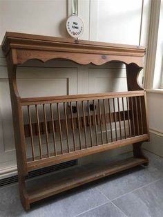 a wooden baby crib in front of a window with a clock on the wall