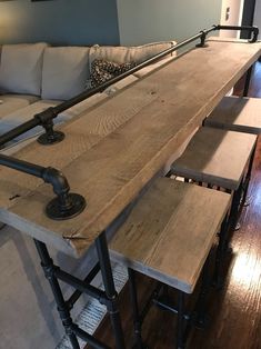 a living room with a couch, table and stools on the hardwood flooring