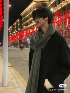 a man standing next to a street with red lanterns on the side of it at night