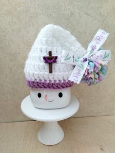 a small crocheted hat with a cross on it and a ribbon around the brim