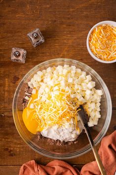 a bowl filled with cheese, eggs and other ingredients on top of a wooden table