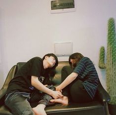 two people sitting on a couch with their hands together