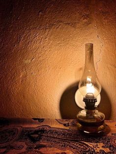 a lamp that is sitting on top of a table next to a wall with a light in it