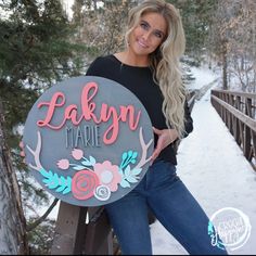 a woman standing on a bridge holding a sign that says laken marie with flowers