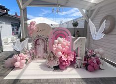 a pink and white birthday party with balloons, decorations and fairy figures on the ground