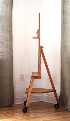 a wooden shelf sitting on top of a hard wood floor next to a curtained window